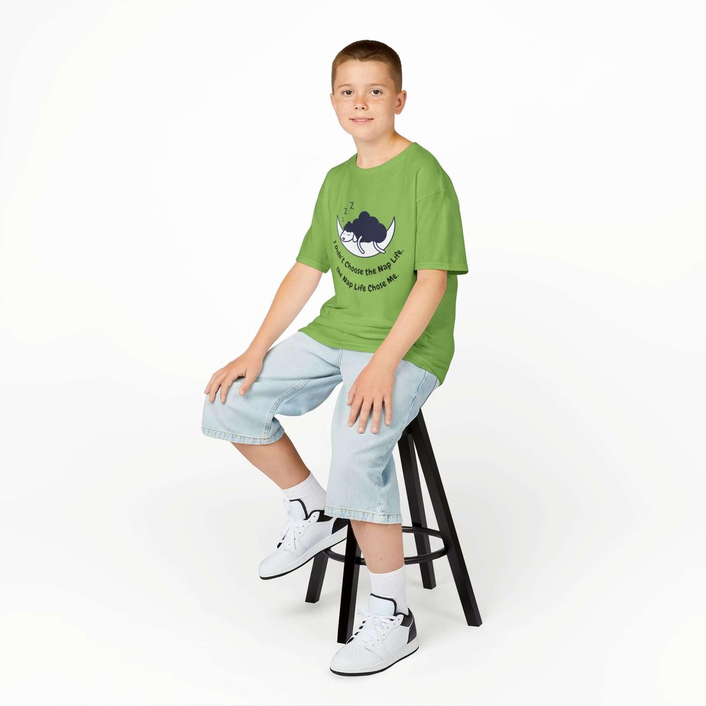 Child wearing a green 'Nap Time' funny T-shirt for kids, sitting on a stool, showcasing comfortable cotton fabric and durable design.