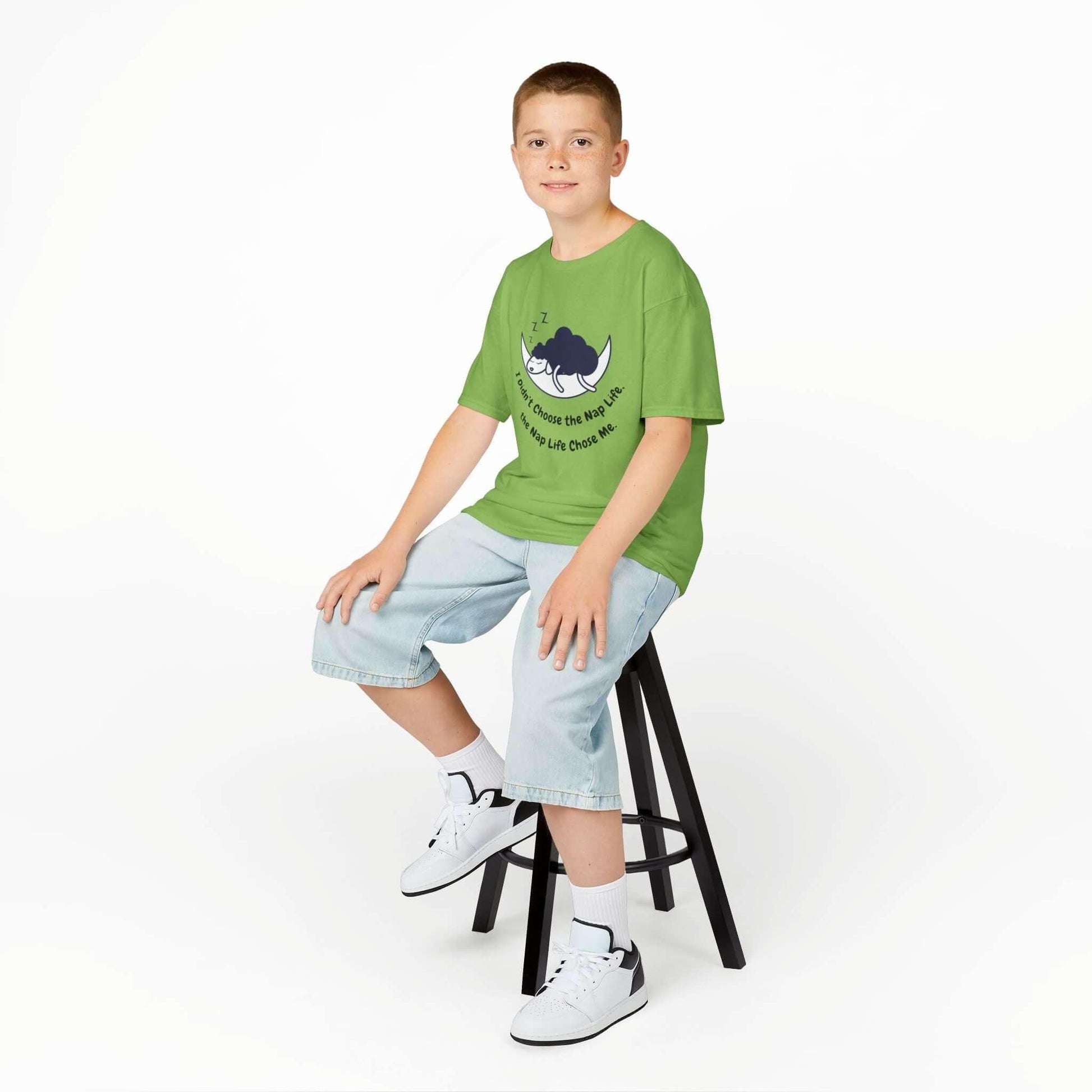 Child wearing a green 'Nap Time' funny T-shirt for kids, sitting on a stool, showcasing comfortable cotton fabric and durable design.