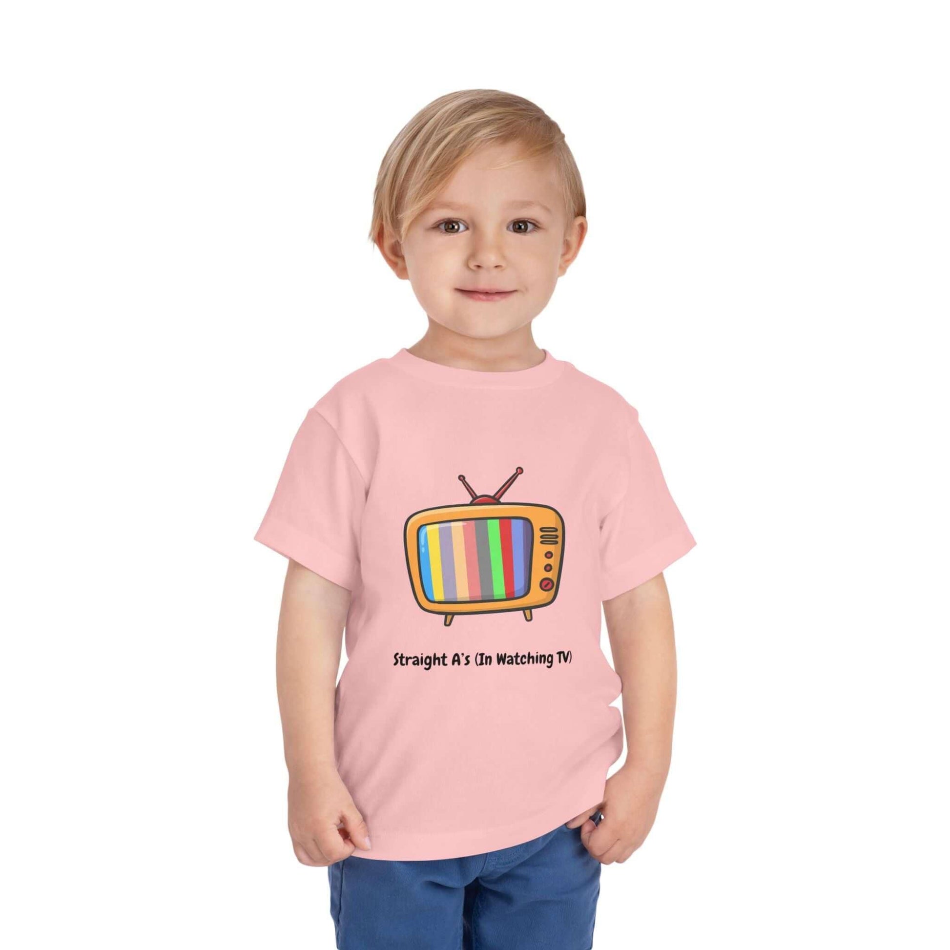 Toddler wearing a pink funny t-shirt with a cartoon TV design and 'Straight A's on Watching TV' caption, made from soft cotton.