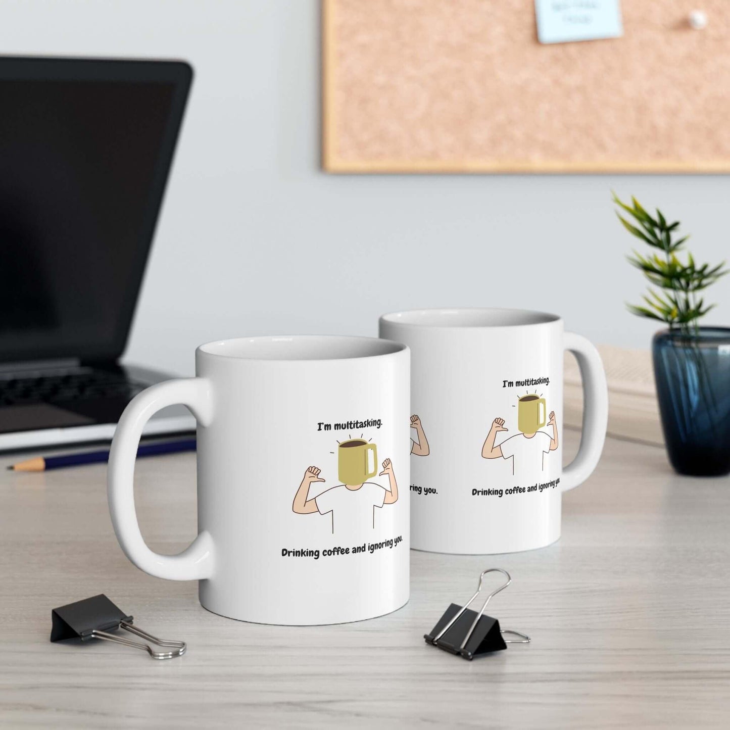 Two ceramic mugs with a funny multitasking design on a desk, ideal for coffee break, available in 11oz and 15oz sizes.