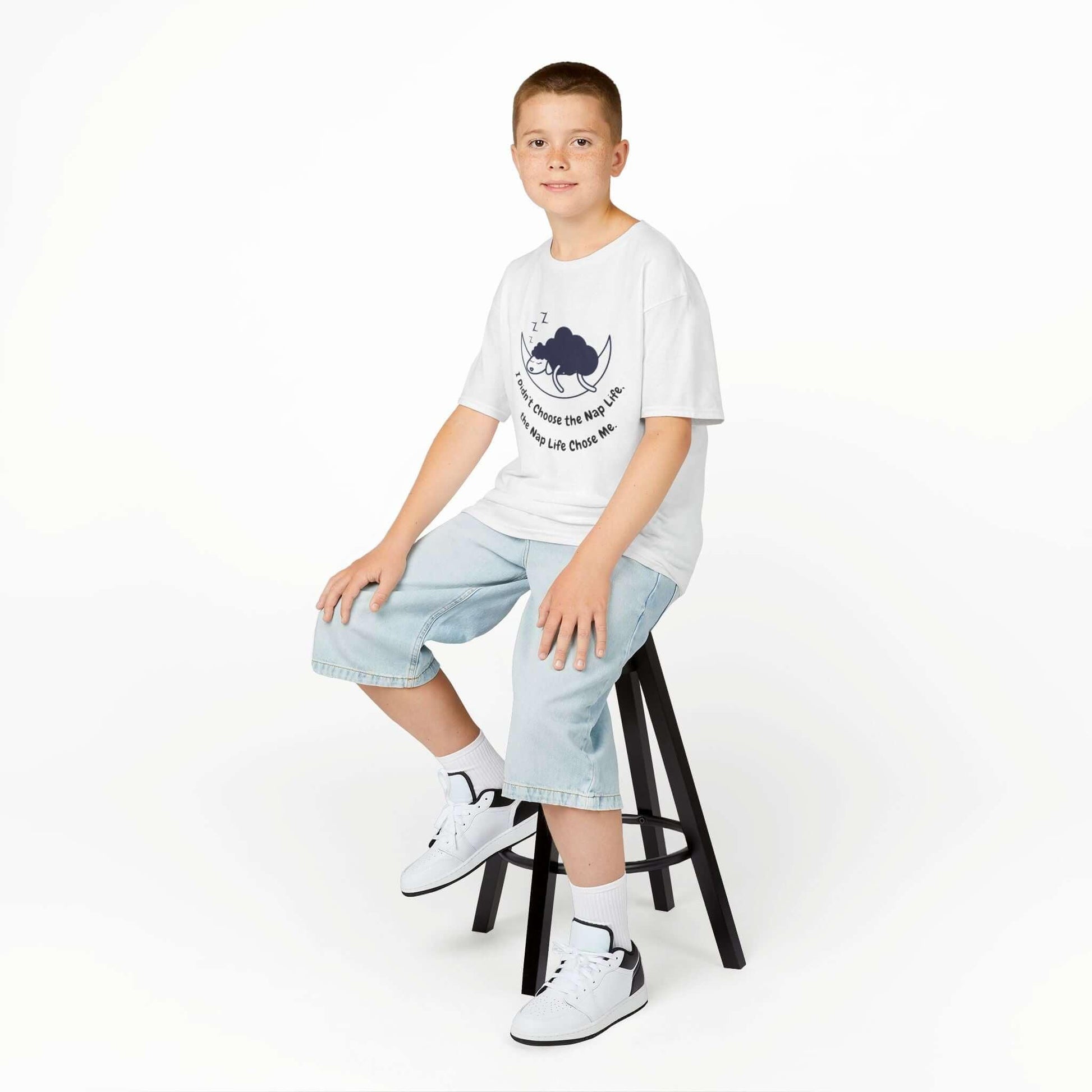 Boy wearing funny nap time T-shirt sitting on stool, showcasing kids' heavy cotton tee made from 100% cotton solid color with ribbed knitting collar.