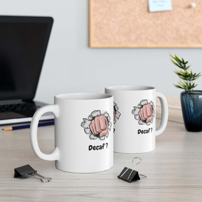 Two white ceramic mugs with 'Decaf?' text and fist graphic on office desk.