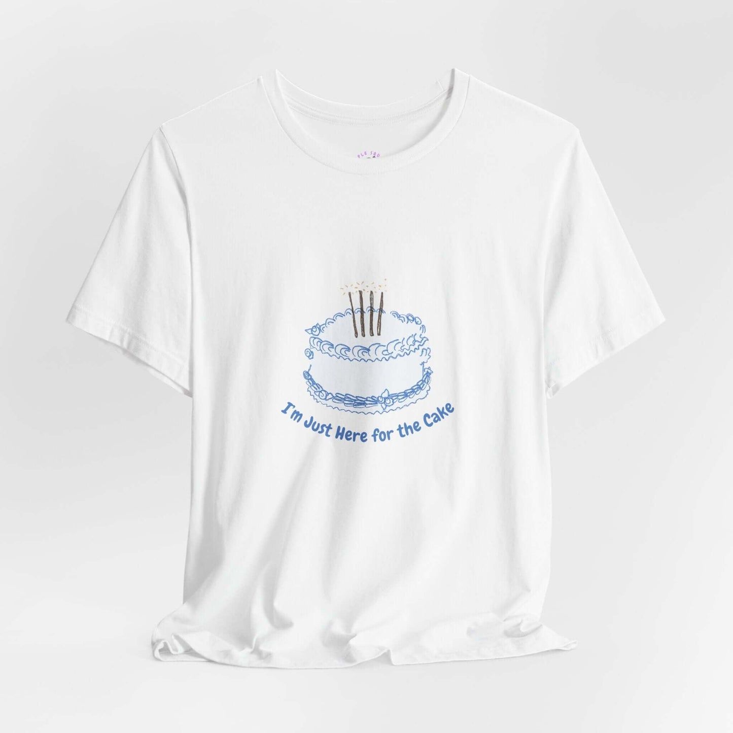 White women's t-shirt with "I'm Just Here for the Cake" graphic featuring a blue cake illustration, made of soft cotton.