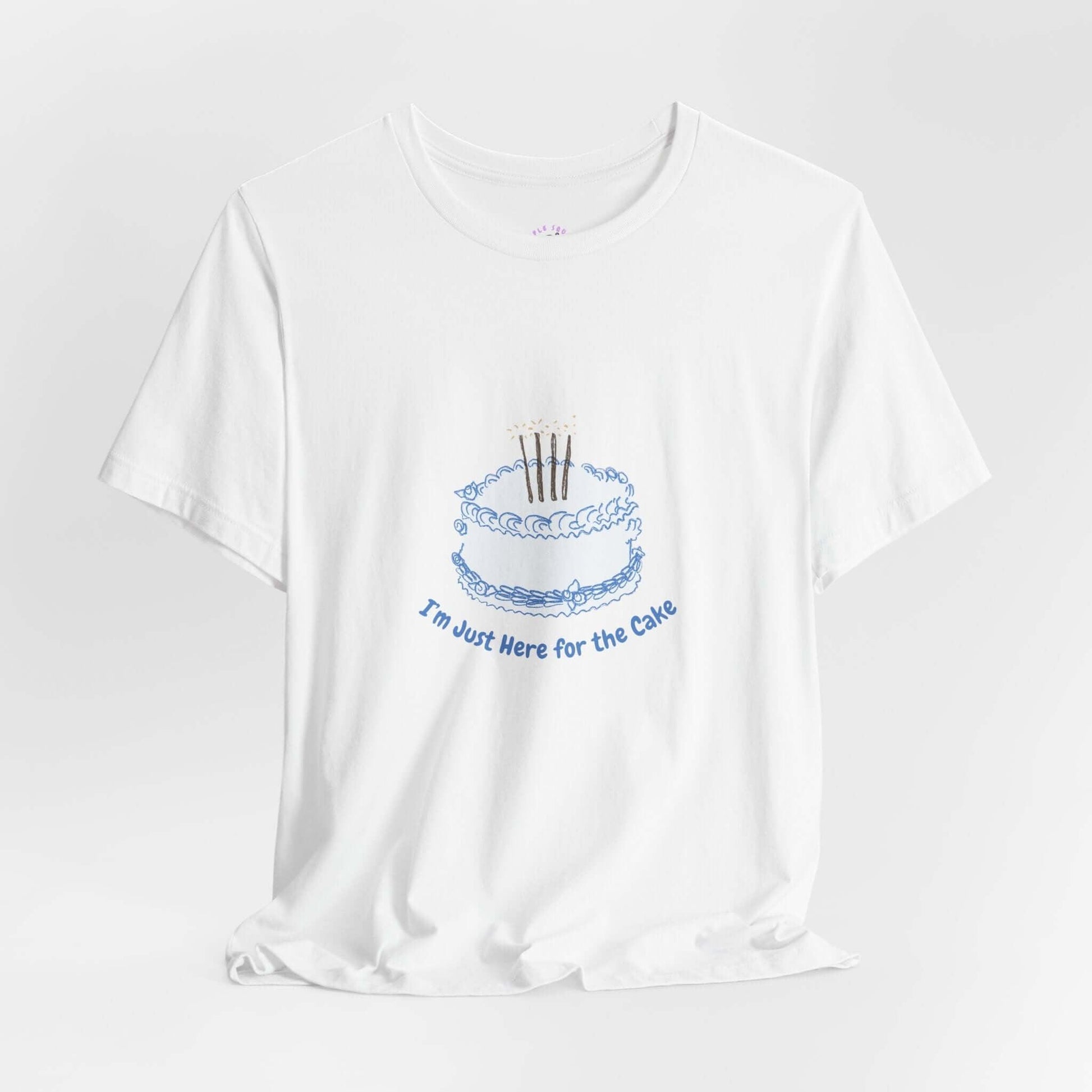 White women's t-shirt with "I'm Just Here for the Cake" graphic featuring a blue cake illustration, made of soft cotton.