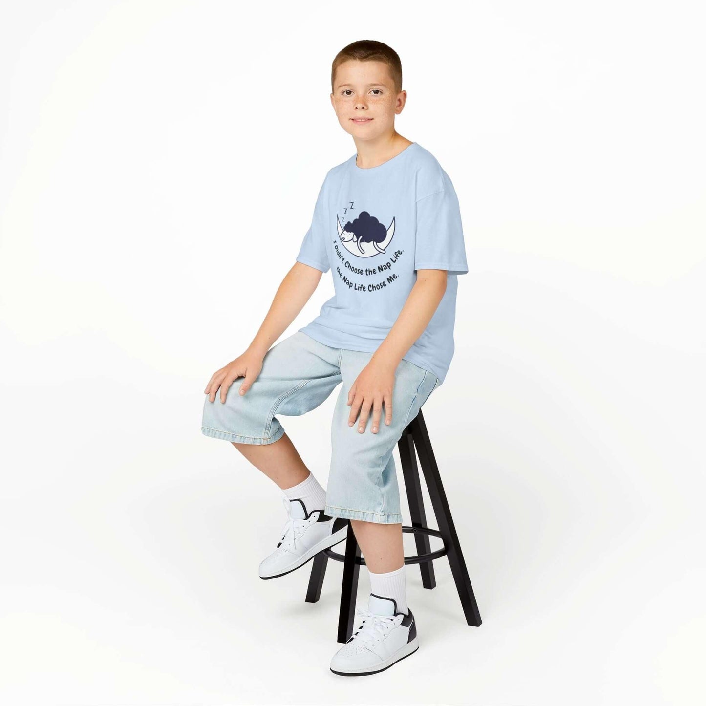 Child wearing a funny t-shirt with nap time graphic, sitting on a stool, showcasing durable and curl-resistant collar.