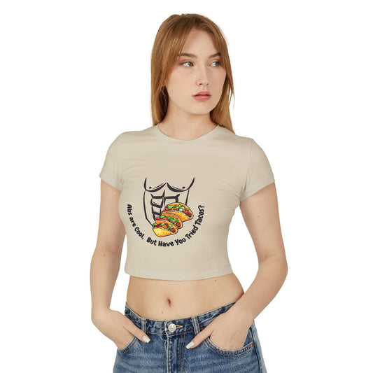 Woman wearing a funny Abs Vs Tacos baby tee, featuring a slim fit and taco graphic, made from organic cotton. Casual and stylish look.