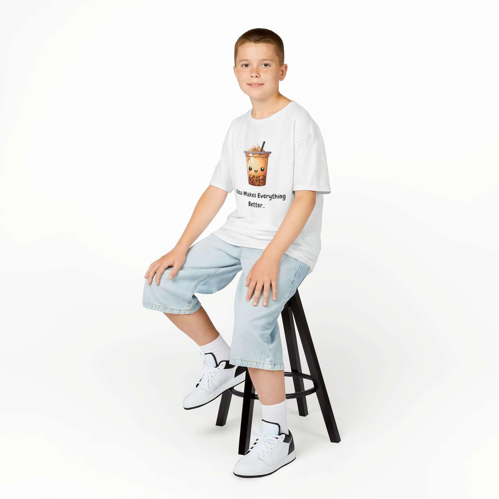 Young boy wearing a 'Bobba is Better' funny T-shirt sitting on a stool, showcasing the casual and durable cotton tee for kids.