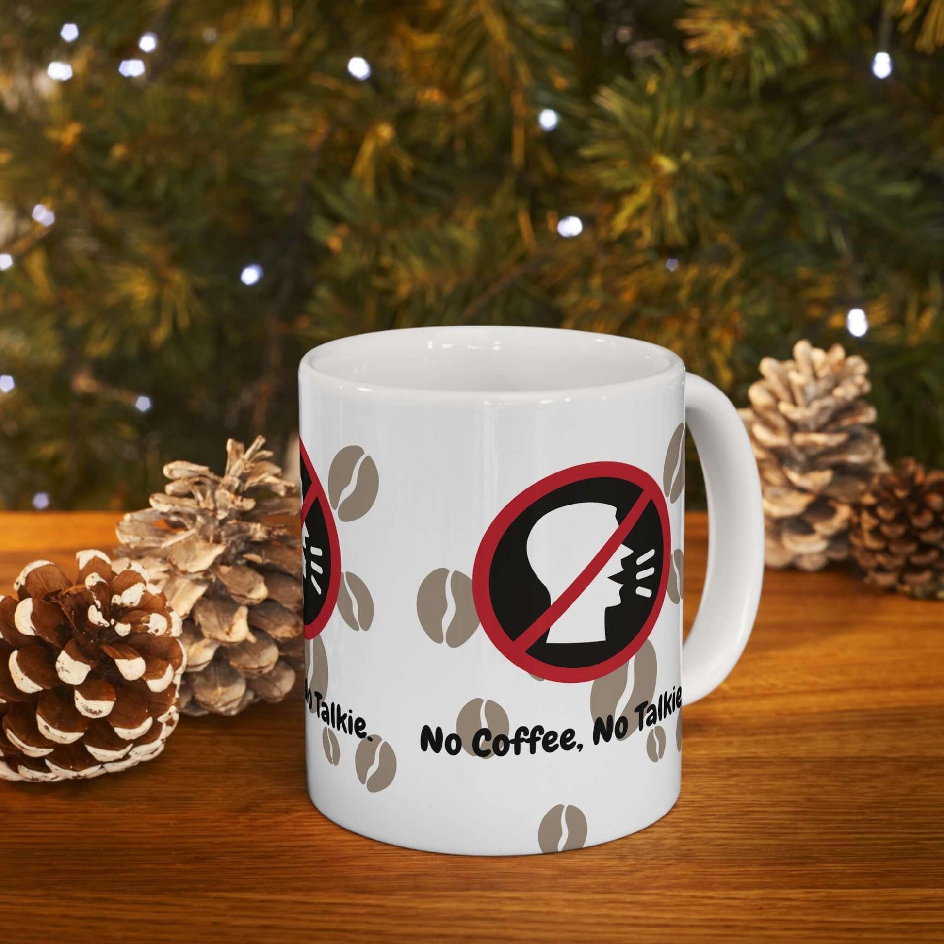 Ceramic coffee mug with 'No Coffee, No Talkie' design, pinecones, and Christmas tree lights background.