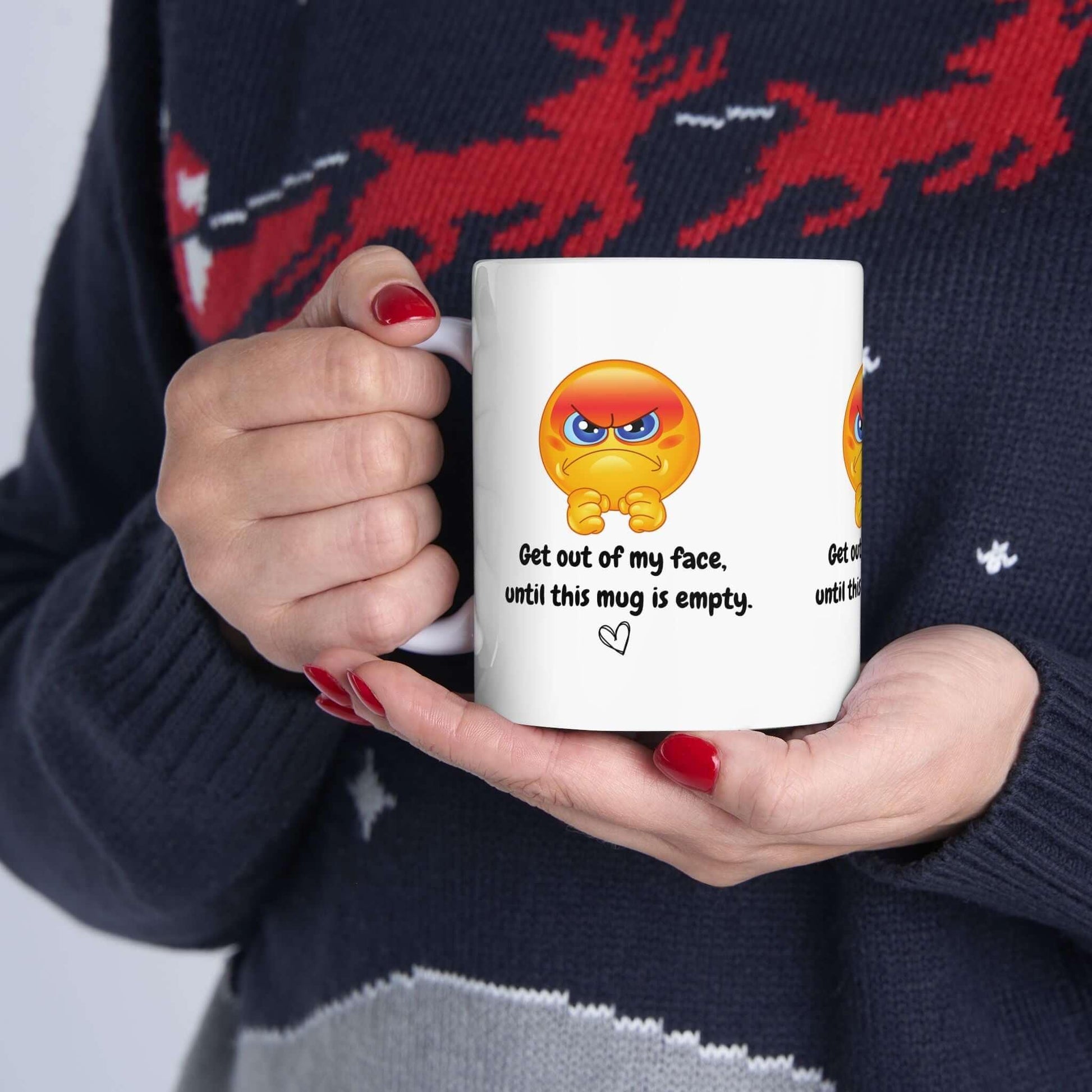 Funny ceramic mug with 'Get out of my face' design, held by person in festive sweater. Perfect gift, BPA-free, available in 11oz and 15oz sizes.