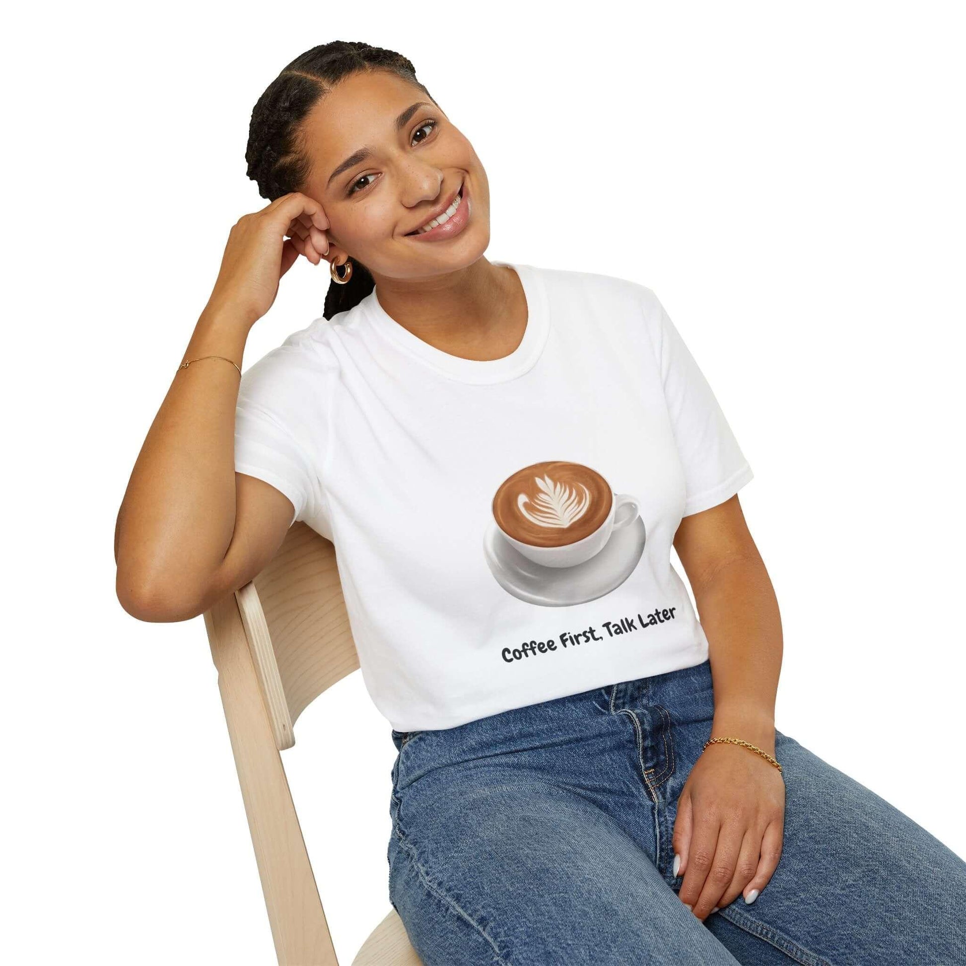 Woman wearing 'Coffee First Talk Later' funny T-shirt with coffee cup graphic, sitting on chair, promoting casual comfort and style.